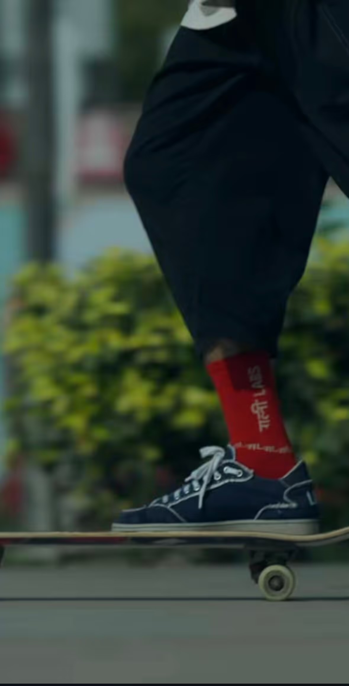 Close-up of a skateboarder's red socks and sneakers on a board