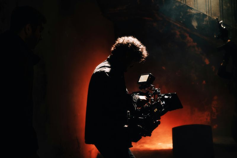 Camera operator silhouetted against warm backlight