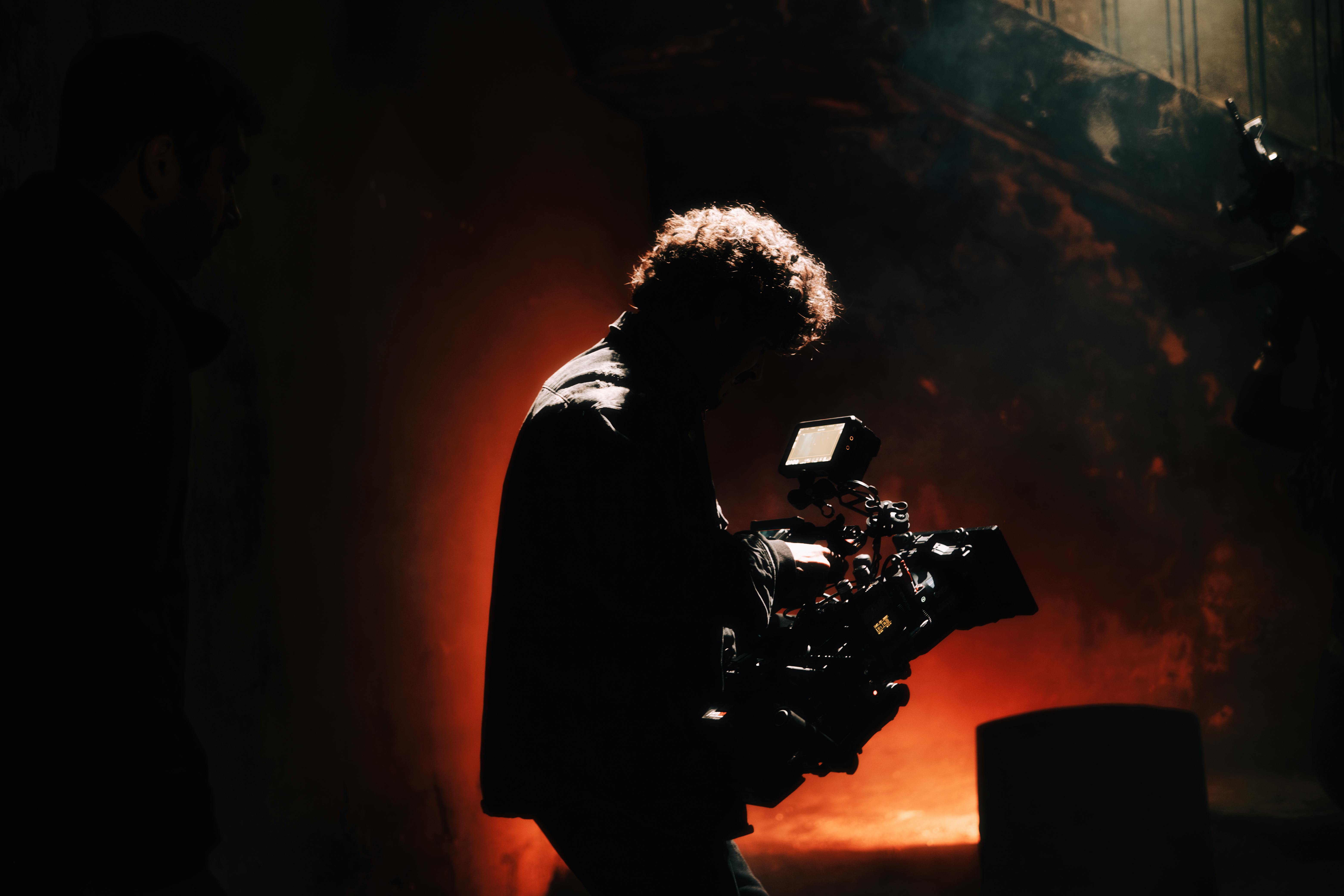 Camera operator silhouetted against warm backlight